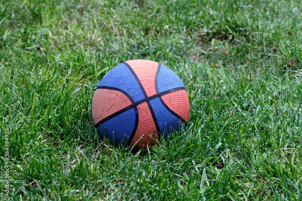 Basketball ball on the grass. Basketball ball waiting for children. Green grass and worn basketball ball. Basketball ball on the grass. Basketball ball waiting for children. Green grass and worn basketball ball.
