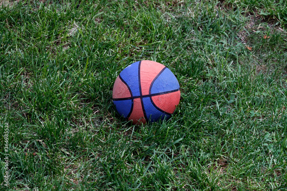 Basketball ball on the grass. Basketball ball waiting for children. Green grass and worn basketball ball. Basketball ball on the grass. Basketball ball waiting for children. Green grass and worn basketball ball.