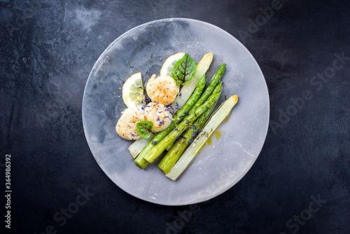 Traditional barbecue scallops with green and white asparagus as top view on a modern design plate with copy space