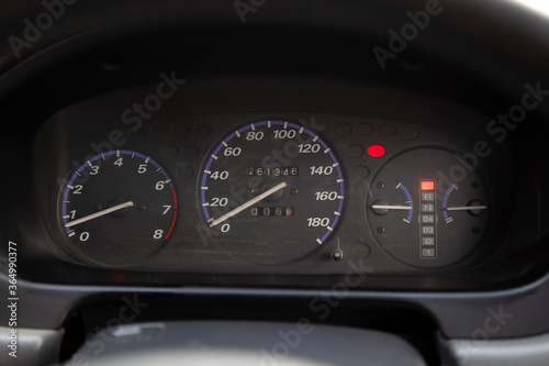 Car dashboard with red instrument circles with backlit arrows at night with a speedometer, tachometer with a mechanical gearshift gearbox to monitor the condition of the car on a black background.