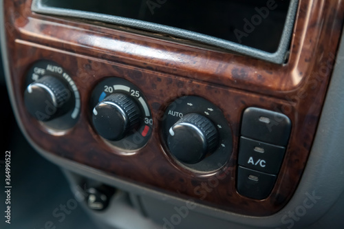 The central control console on a brown decorated panel inside the car close-up with buttons and climate control toggle switches. © Aleksandr Kondratov