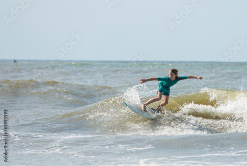 A young boy surfs waves on the Atlantic Ocean.