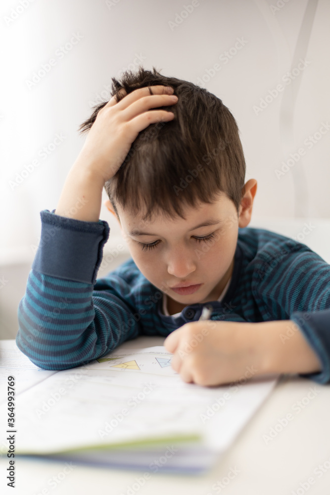 Portrait of young boy struggling with his homework at home. Children home education concept. Distance learning Portrait of young boy struggling with his homework at home. Children home education concept. Distance learning
