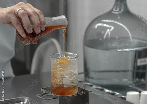Barista hand holding Lab Borosilicate Glass Beaker Mixing tea drink beverage In Chemistry Bar Beaker Cocktail.