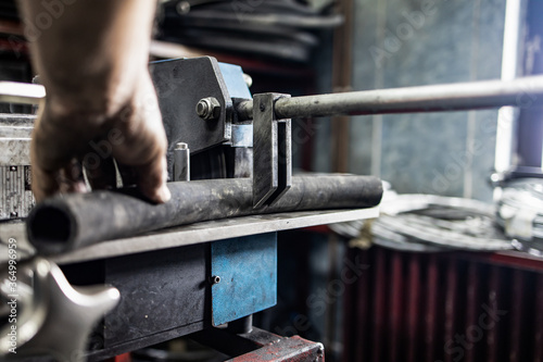 Worker, cutting hydraulic hoses in a metal workshop