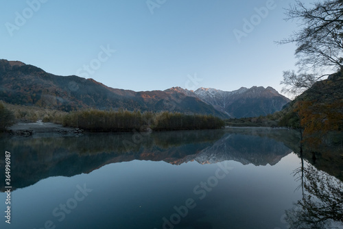 紅葉の上高地・大正池から見た朝日に照らされる穂高連峰 © homebell