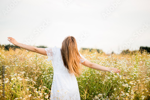 Happy girl on the camomile field, summer sunset. in a white dress. running and spinning, the wind in my hair, life style. freedom concept and hot summer