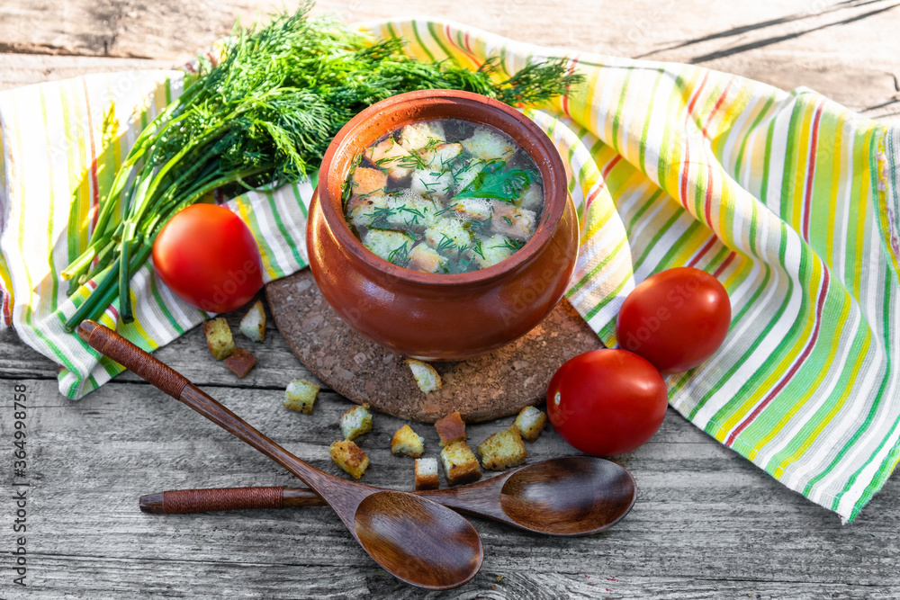 Delicious broth with croutons, dill, tomatoes on an old wooden background. Lunch with soup in a clay pot vegetarian in the open air. Delicious broth with croutons, dill, tomatoes on an old wooden background. Lunch with soup in a clay pot vegetarian in the open air.