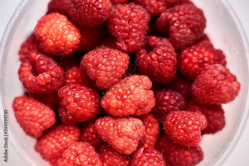 Ripe raspberries in a transparent bucket. Top view.