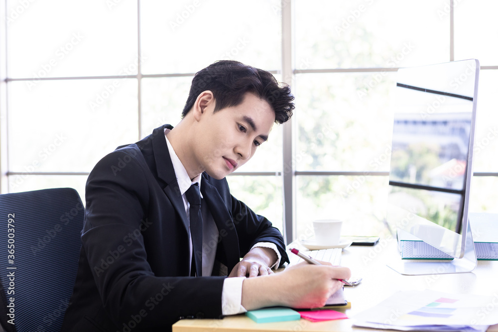 Happy mood a cheerful of asian young businessman have ideas make a note the successful business plan in document paper and computer on wooden table background in office. Happy mood a cheerful of asian young businessman have ideas make a note the successful business plan in document paper and computer on wooden table background in office.