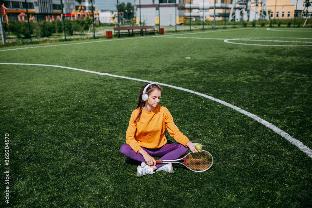 Obraz premium Woman playing on the tennis court. Woman holding tennis racket and ball on the green grass.