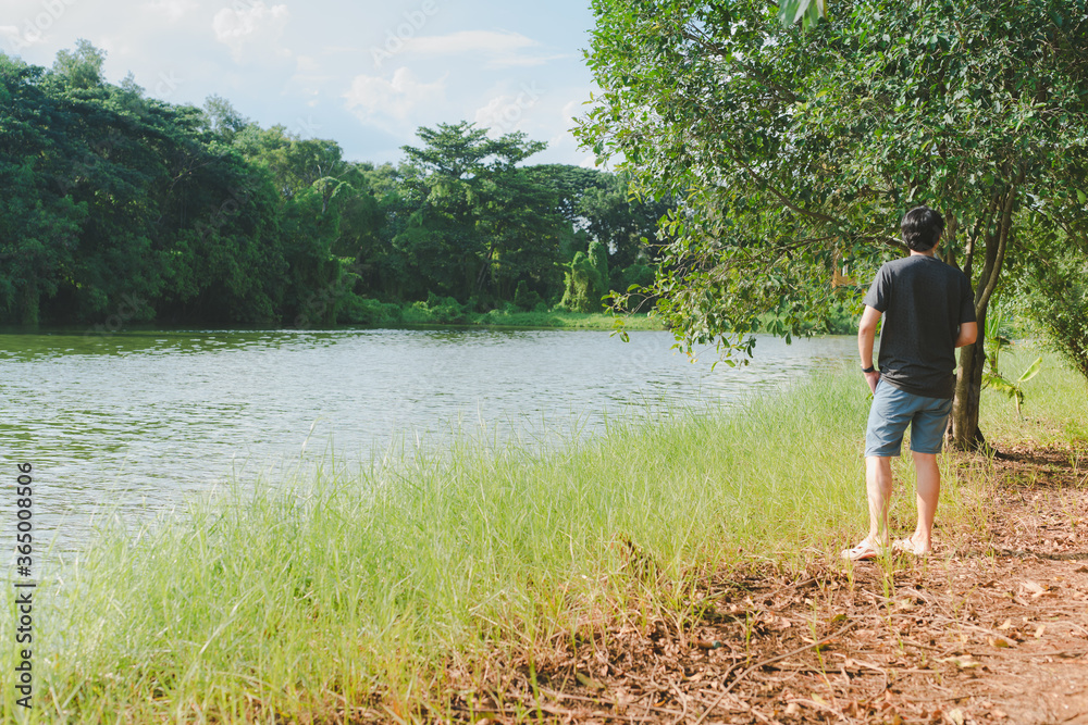 relax and lifestyle activity from asian man 30s to 40s during stand at side of river and under tree on spring season with happiness feeling with sunset background relax and lifestyle activity from asian man 30s to 40s during stand at side of river and under tree on spring season with happiness feeling with sunset background
