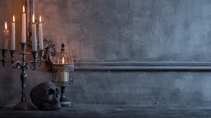 Mystical Halloween still-life background. Skull, candlestick with candles, old fireplace. Horror and witchery.