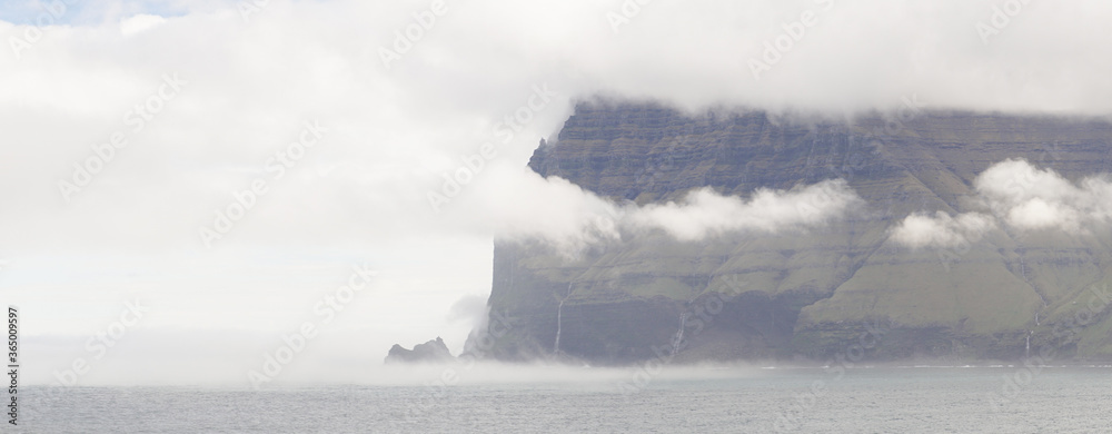 Steep mountain cliffs next to the ocean on Kalsoy Island in the Faroe Islands, Denmark.
