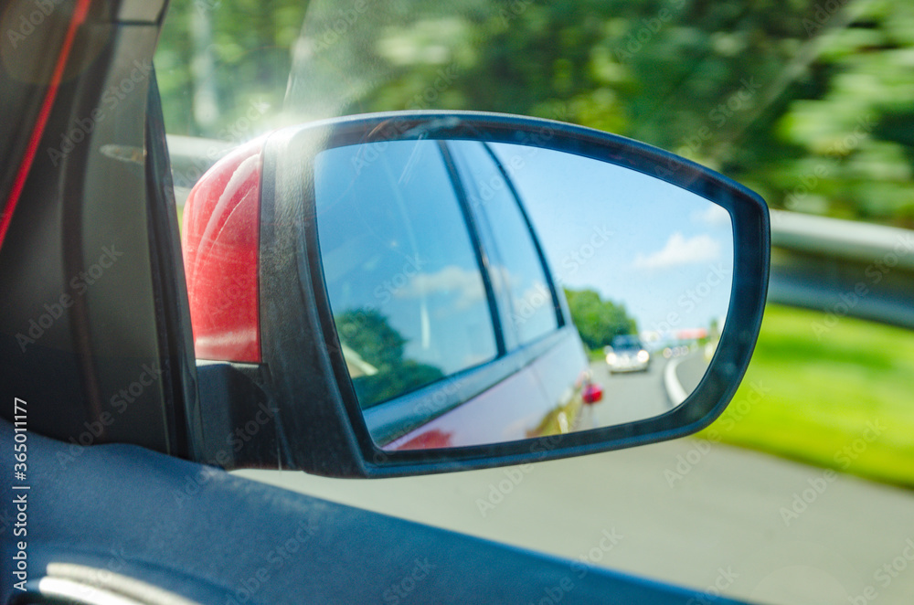 Reflection of blurred car in the rearview mirror on highway in beautiful sunny day Reflection of blurred car in the rearview mirror on highway in beautiful sunny day