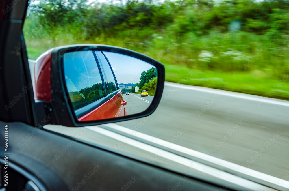 Reflection of blurred cars in the rear view mirror on highway