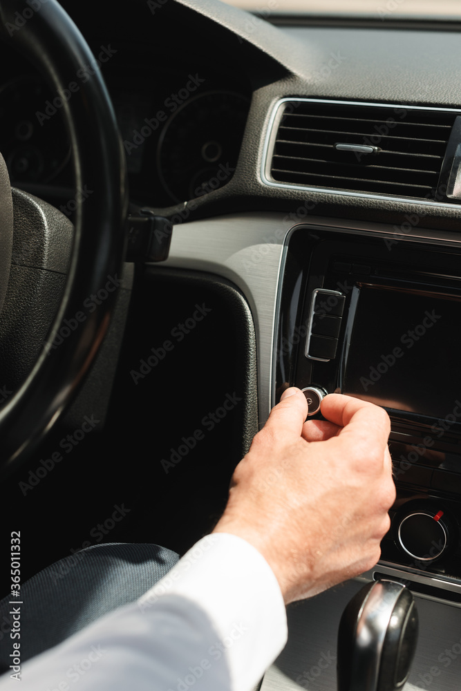 Cropped view of businessman adjusting volume of vehicle audio system in auto Cropped view of businessman adjusting volume of vehicle audio system in auto