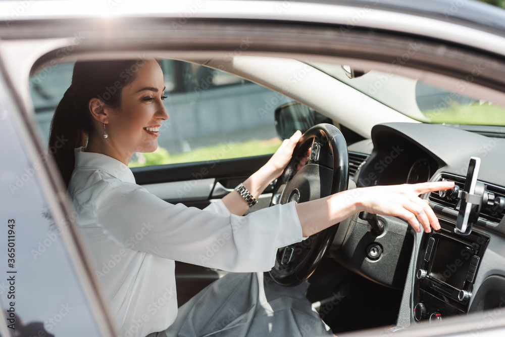 Side view of smiling businesswoman using smartphone while driving auto