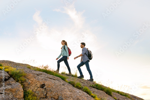 Couple of Young Happy Travelers Hiking with Backpacks on the Rocky Trail at the Evening. Family Travel and Adventure © Maksym Protsenko