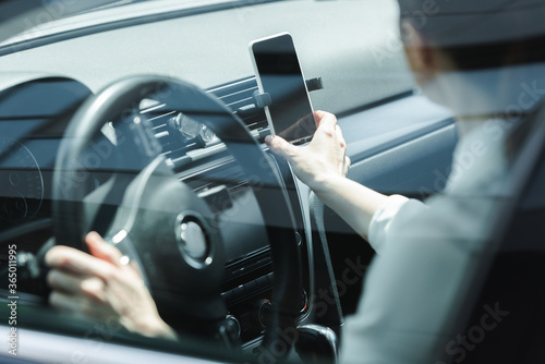 Selective focus of businesswoman holding smartphone while driving car