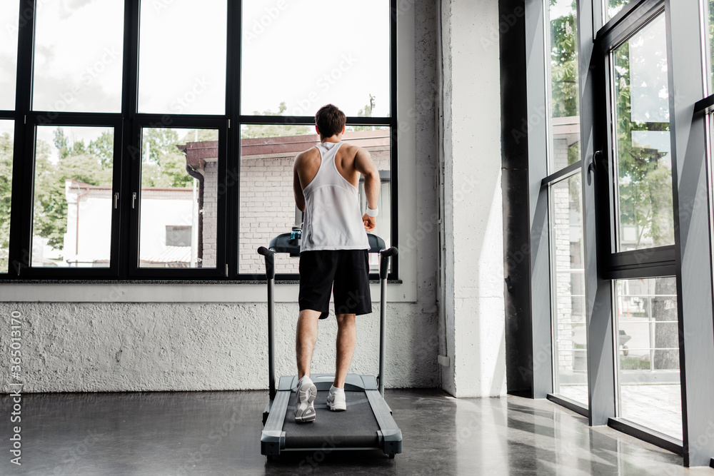 back view of man running on treadmill in gym back view of man running on treadmill in gym
