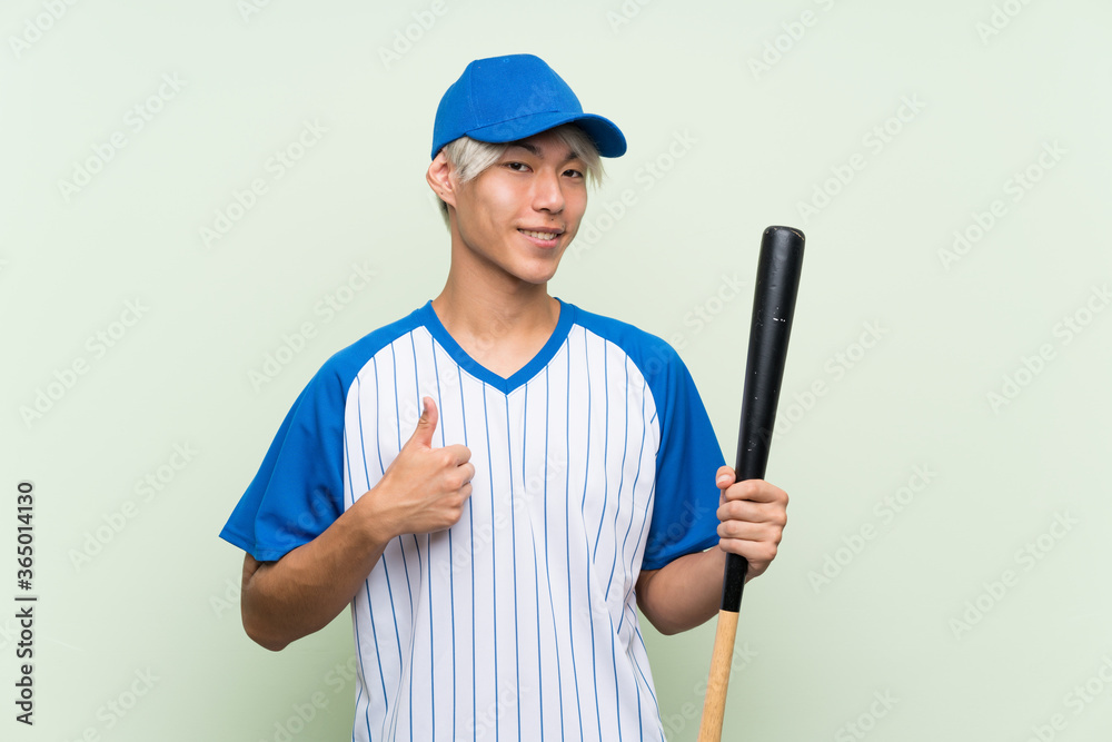 Young asian man playing baseball over isolated green background with thumbs up because something good has happened