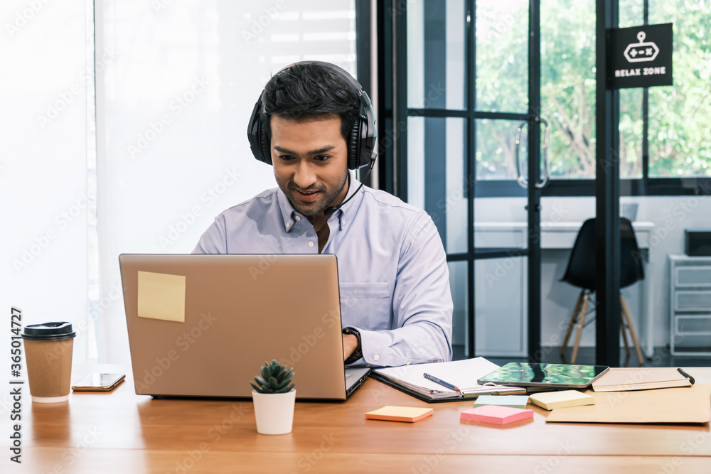 An Asian teenage man is sitting on a desk with a notebook. He is a company manager. he works hard to make the company successful. An Asian teenage man is sitting on a desk with a notebook. He is a company manager. he works hard to make the company successful.