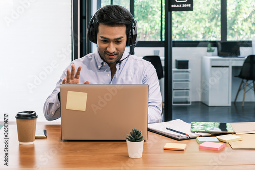An Asian teenage man is sitting on a desk with a notebook. He is a company manager. he works hard to make the company successful.