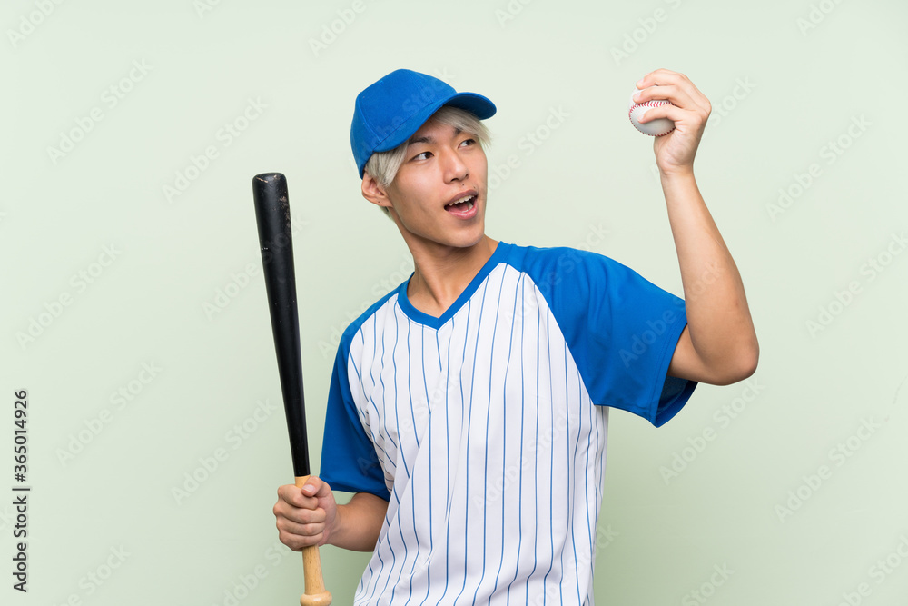 Young asian man playing baseball over isolated green background Young asian man playing baseball over isolated green background