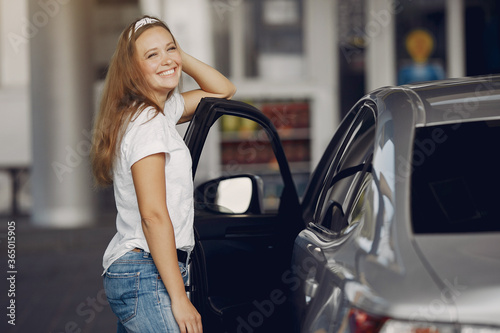 Woman by the car. Lady in a white t-shirt.