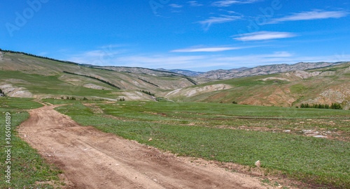 Dirt track leading up a Mongolian grassland valley on a summer day photo