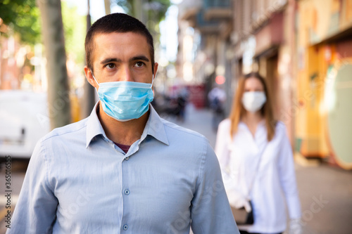 Man in protective face mask for spreading of virus disease prevention walking on city street during pandemic situation