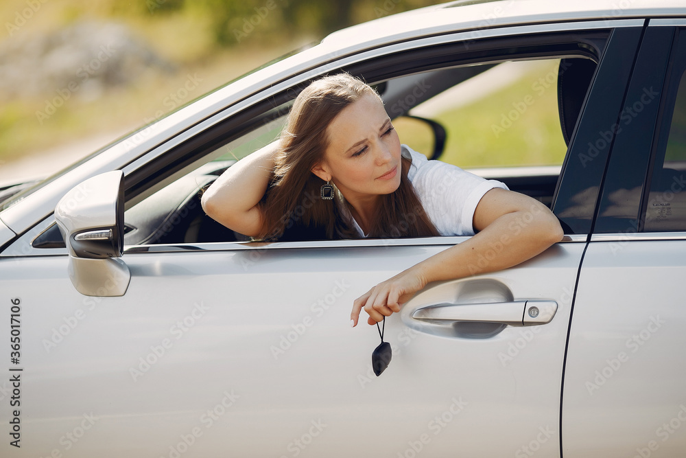 Woman in a car. Lady in a white t-shirt. Famale hold the keys in her hands.