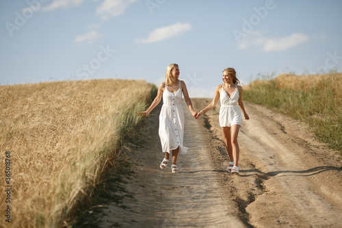 Adult mother with daughter. Beautiful girl in a white dress. Family in a summer field