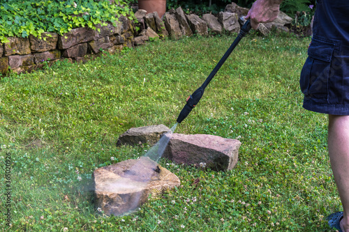 Man cleans two old sandstones with a high-pressure cleaner