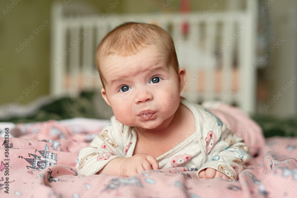 small child lies on his stomach, drooling with bubbles on lips, girl holds her head with difficulty small child lies on his stomach, drooling with bubbles on lips, girl holds her head with difficulty