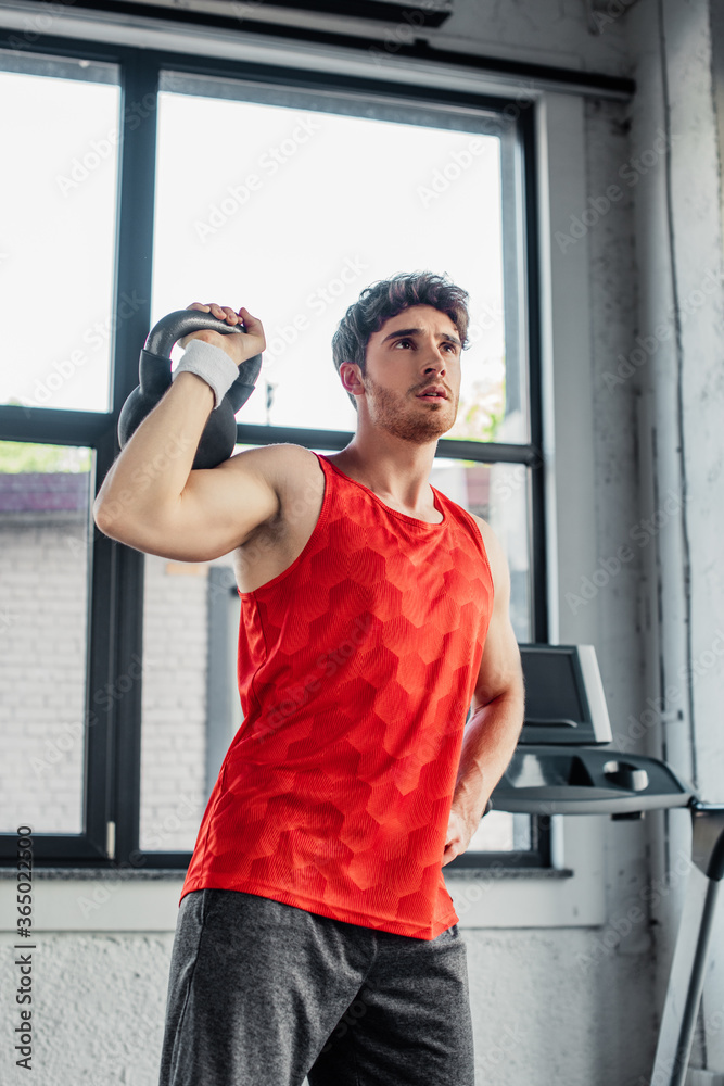 sportive man working out with dumbbell while standing with hand on hip sportive man working out with dumbbell while standing with hand on hip