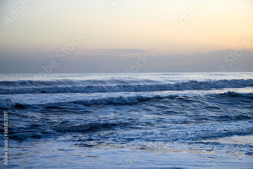 Water of sea with waves and yellow sky at sunset.