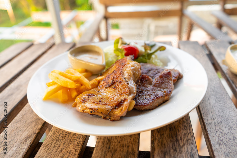 Meat plate of steaks and fries. Chicken and meat on a plate with potatoes in a summer cafe. Meat plate of steaks and fries. Chicken and meat on a plate with potatoes in a summer cafe.