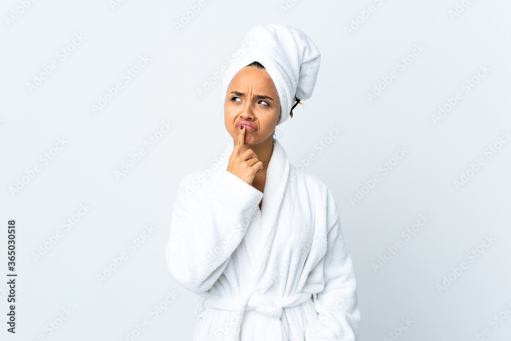 Young woman in bathrobe over isolated white background having doubts while looking up Young woman in bathrobe over isolated white background having doubts while looking up