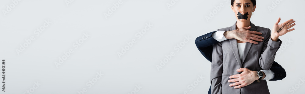 Φωτογραφία panoramic crop of businessman molesting businesswoman with scotch tape on mouth