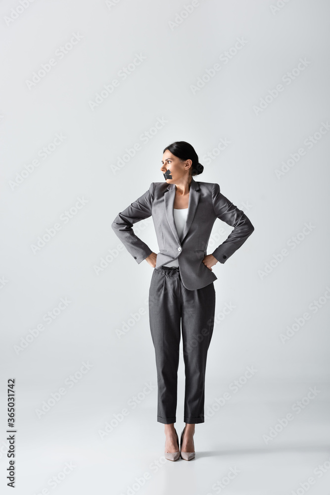businesswoman with scotch tape on mouth standing with hands on hips on white, gender inequality concept businesswoman with scotch tape on mouth standing with hands on hips on white, gender inequality concept