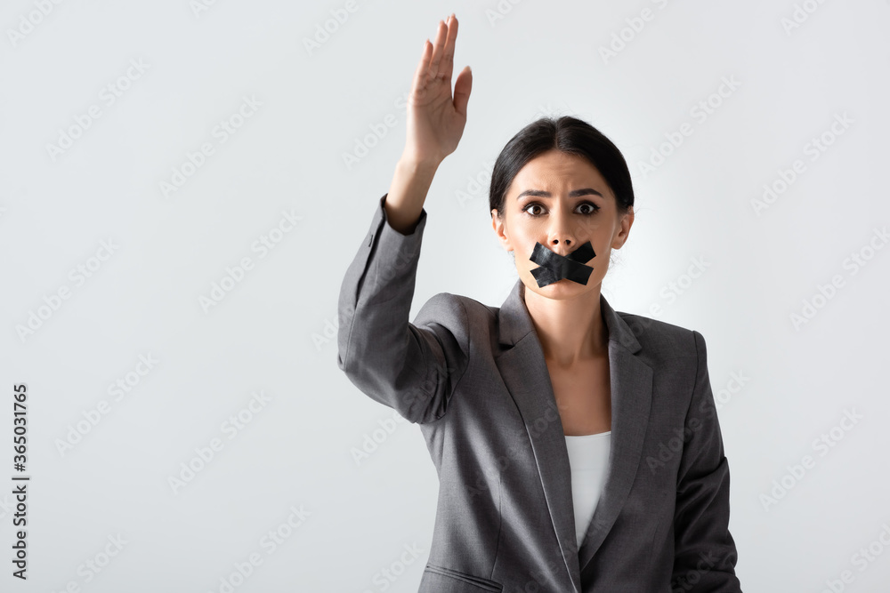 Φωτογραφία businesswoman with scotch tape on mouth raising hand and looking at camera isola