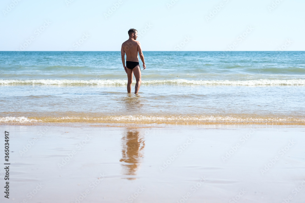 Chico joven guapo en bañador en la playa