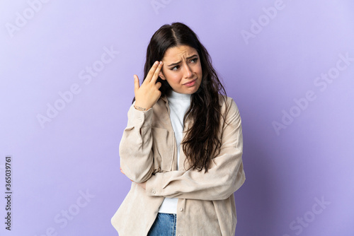 Young caucasian woman isolated on purple background with problems making suicide gesture
