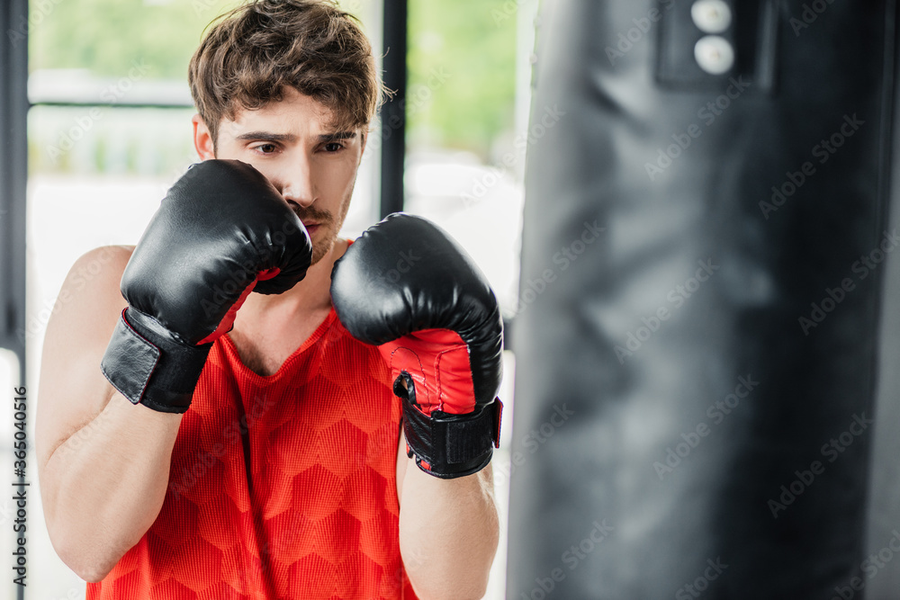 selective focus of athletic man in boxing gloves exercising with punching bag selective focus of athletic man in boxing gloves exercising with punching bag