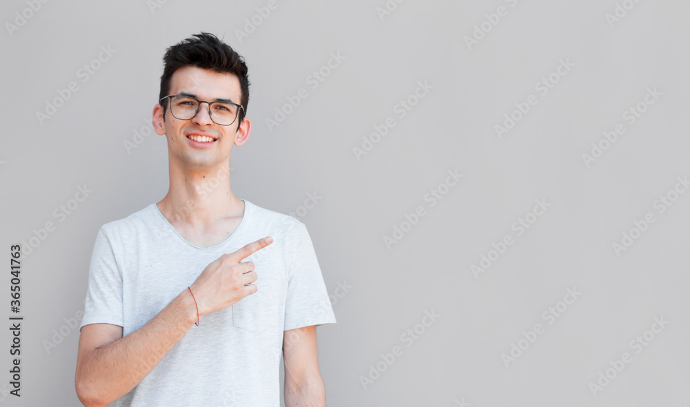 Handsome smiling man pointing away on gray background Handsome smiling man pointing away on gray background