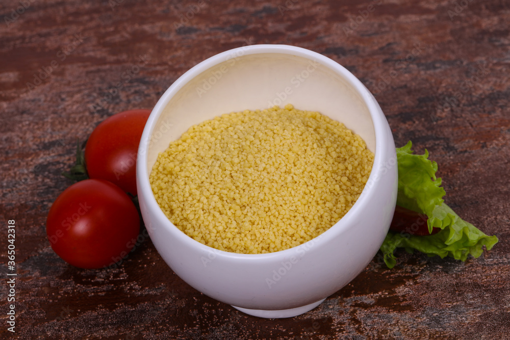 Raw couscous in the bowl served salad leaves, tomato and pepper Raw couscous in the bowl served salad leaves, tomato and pepper