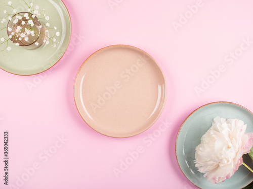 Pastel color tableware ceramic dishes on pink background. Table setting concept. Flat lay, mock up with floral decor