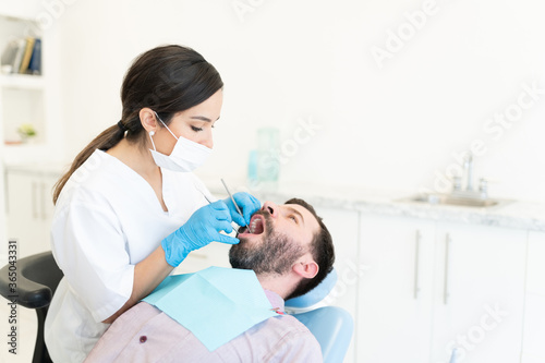 Odontologist Examining Teeth Of Mid Adult Man
